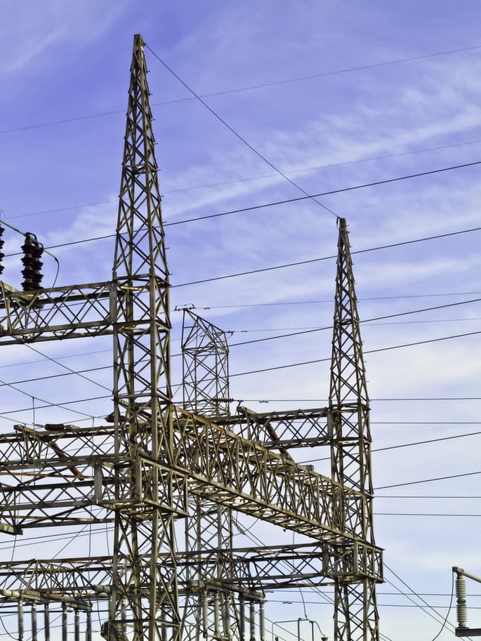 Architecture of electricity Part of electrical substation with steel lattice structures under blue sky with fading contrails